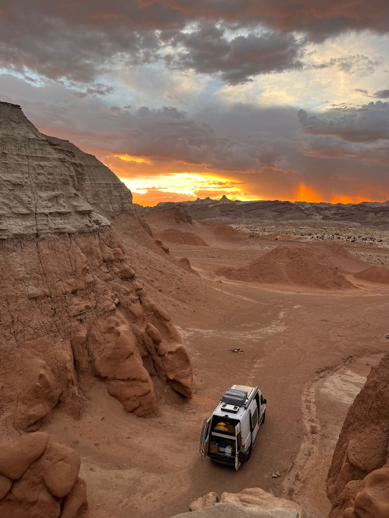 Golden sunset lights a white RV rental parked in a rugged desert valley with towering cliffs. A perfect spot for remote adventure. — photo 14