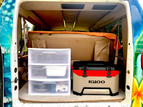 Rear view of RV rental van's organized interior: clear drawers with kitchenware & an Igloo cooler.