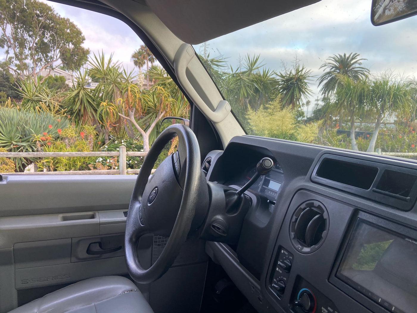 RV rental Ford E-Series van interior showing dashboard, steering wheel, and a lush, tropical landscape outside. — photo 10