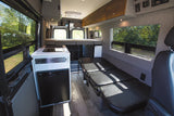 Explore this modern RV rental's cozy camper van interior: kitchen, raised bed, and versatile seating.