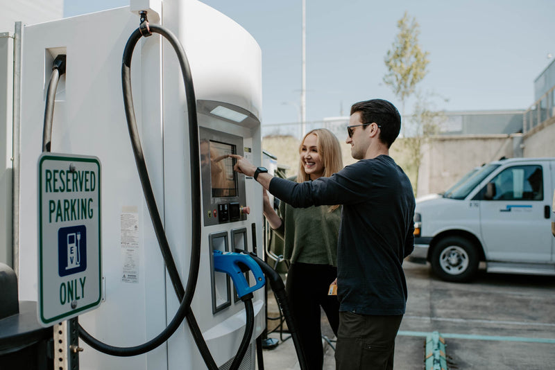 Two people use an electric vehicle charging station. EV charging is essential for modern travel planning, even alongside an rv rental. — photo 13