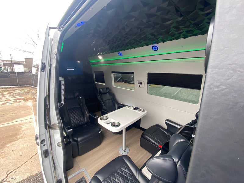 Spacious RV rental interior featuring black leather captain's chairs, a convenient table, and ambient LED lighting. Ideal for comfort. — photo 14