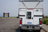 A versatile truck camper, perfect for RV rental adventures, parked at the iconic Grand Teton National Park entrance in Wyoming.