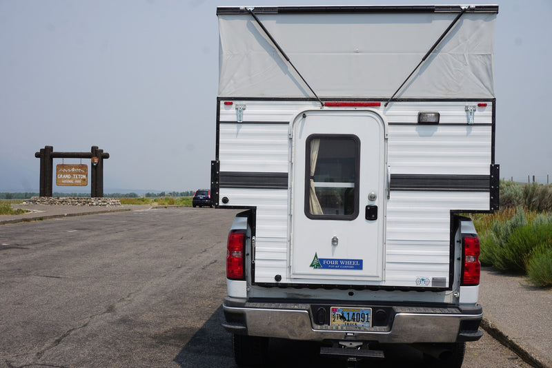 A versatile truck camper, perfect for RV rental adventures, parked at the iconic Grand Teton National Park entrance in Wyoming. — photo 4