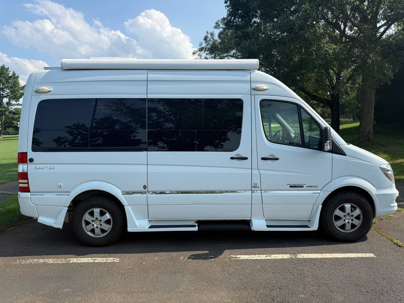  seen from the rear-side.|White Roadtrek SS Agile RV rental (Mercedes-Benz Sprinter camper van) parked by a sunny golf course.|White Roadtrek SS Agile camper van (Mercedes Sprinter) for RV rental — photo 6