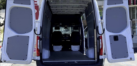 White cargo van with rear doors open, revealing an empty interior, ideal for RV rental conversion.
