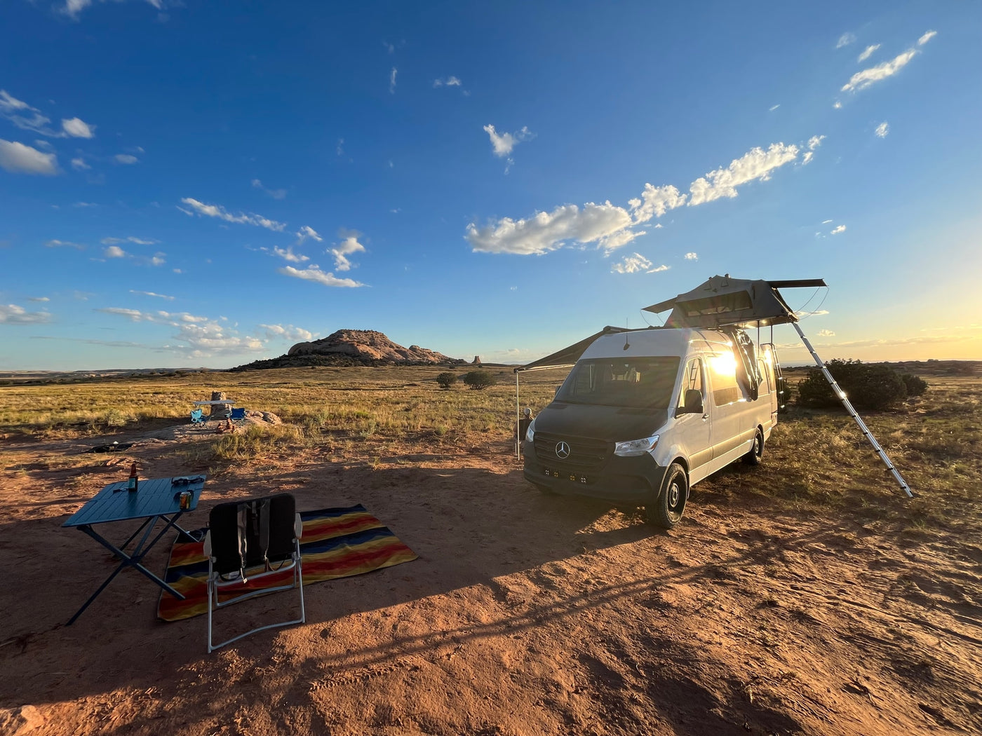 RV rental van with rooftop tent, set up for camping in a scenic desert landscape with mountains. — photo 2