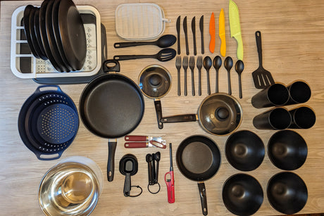 RV rental kitchen setup: frying pans, saucepans, dish rack, collapsible colander, measuring tools, utensils, and bowls.