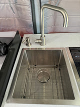 RV rental kitchen area featuring a modern stainless steel sink with faucet, soap dispenser, and part of an adjacent cooktop.