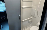 Compact RV rental bathroom features a toilet, shower, and toilet paper holder, perfect for travel and camping.