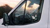 Sun-drenched interior of a white van, showing the steering wheel and dashboard. Ideal for an RV rental trip.