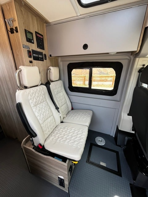  and aisle to rear bed for easy travel.|Comfortable light bench seat inside an RV rental — photo 6