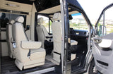 This luxury RV rental's interior boasts cream captain's chairs and wood-look flooring, with open doors showing the driver's area.