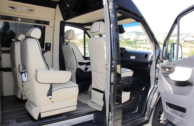 This luxury RV rental's interior boasts cream captain's chairs and wood-look flooring, with open doors showing the driver's area. — photo 6