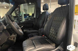Plush black leather diamond-stitched seats fill this RV rental's spacious front cabin. See driver's steering wheel & comfy passenger seat.