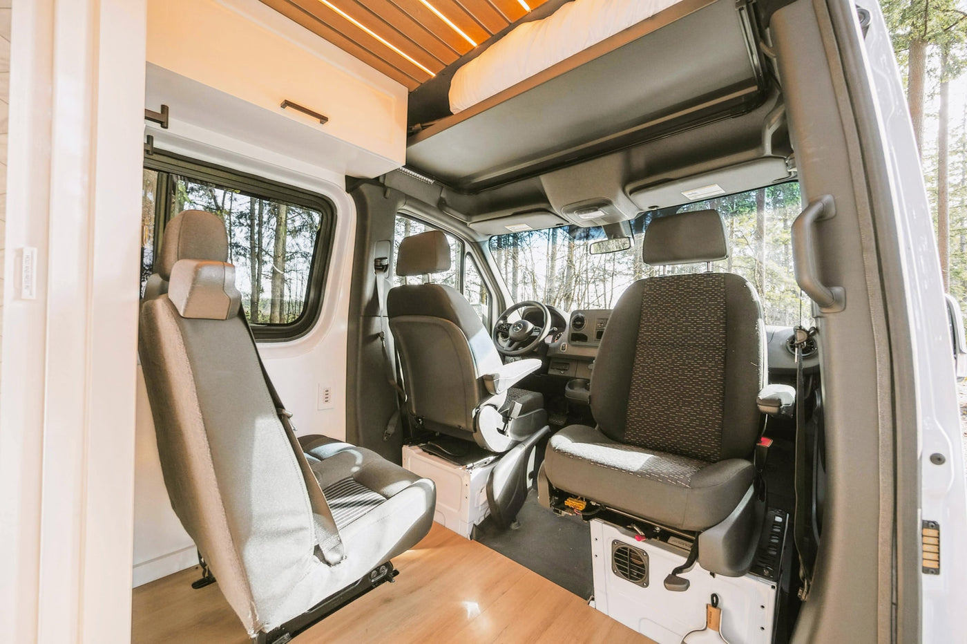 Interior of an RV rental camper van, showing the front seats, dashboard, and custom overhead storage with a slatted ceiling. — photo 6