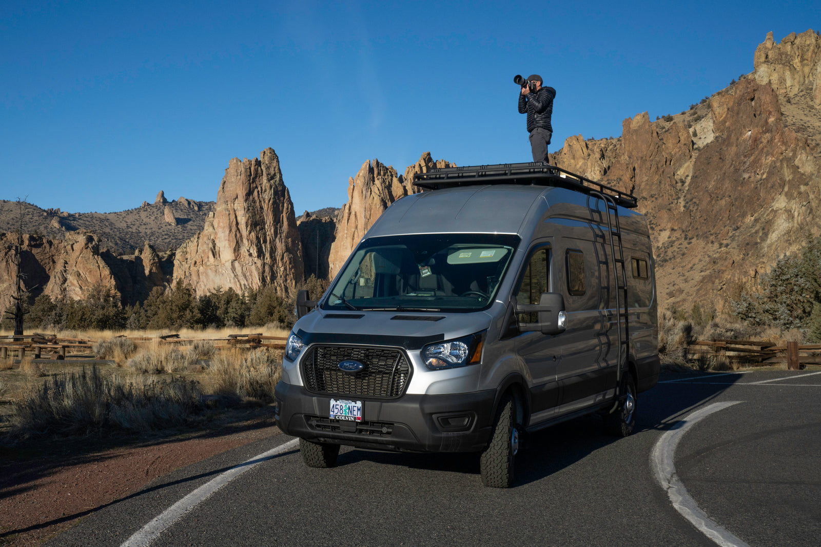 An RV rental provides the perfect vantage for a photographer to capture stunning, rugged landscapes from atop a customized Ford Transit van.