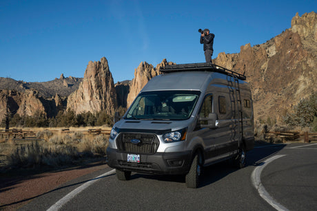 An RV rental provides the perfect vantage for a photographer to capture stunning, rugged landscapes from atop a customized Ford Transit van.
