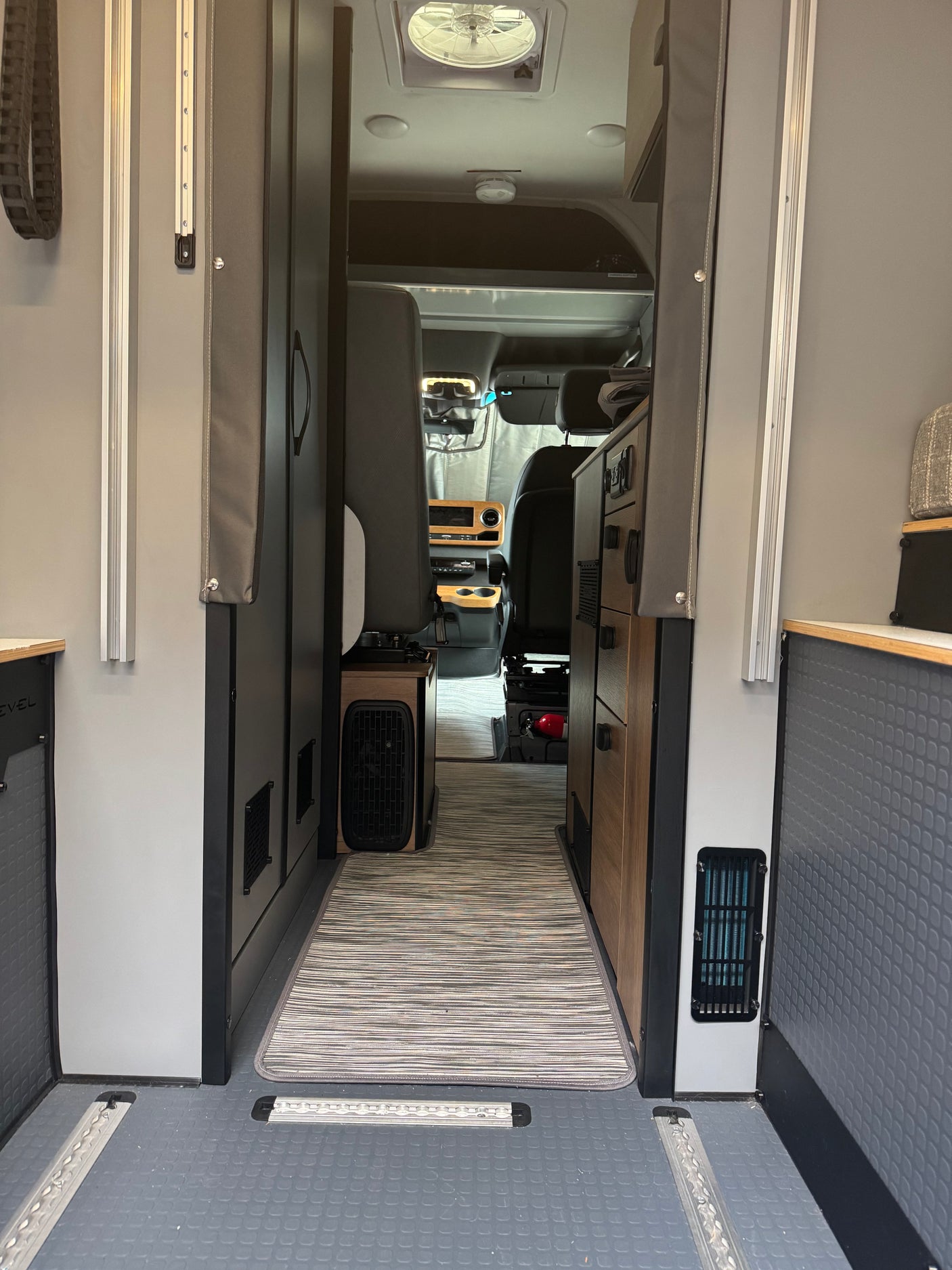 RV rental: Campervan interior hallway with rug, built-in cabinets, and view to front seats/cab. Ready for road trips.