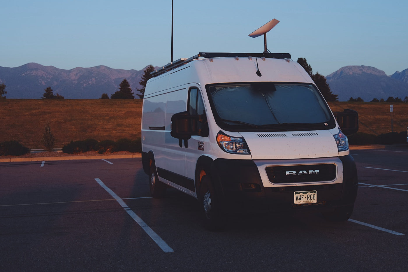 White camper van (RV rental) with Starlink, parked at dusk. Mountains and fields create a scenic backdrop for this Colorado adventure. — photo 16