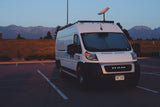 White camper van (RV rental) with Starlink, parked at dusk. Mountains and fields create a scenic backdrop for this Colorado adventure.