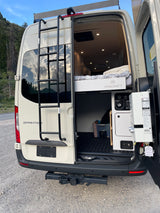 RV rental Sprinter camper van's rear view, with open doors showcasing its VANCRAFT interior, cozy bed, and water system.