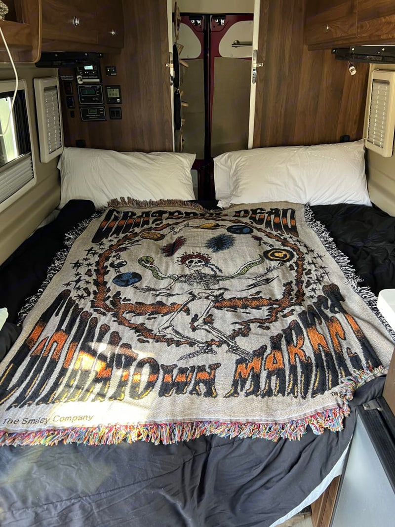  and bed with checkered rug in the main living space.|Two red RV rental vans with solar panels create a cozy outdoor gathering space on wood chips for friends.|This RV rental's compact kitchen boasts a sink — photo 8