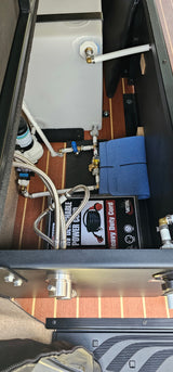 RV rental interior: a compact water system featuring a white tank, pump, plumbing, and power cord for reliable travel.