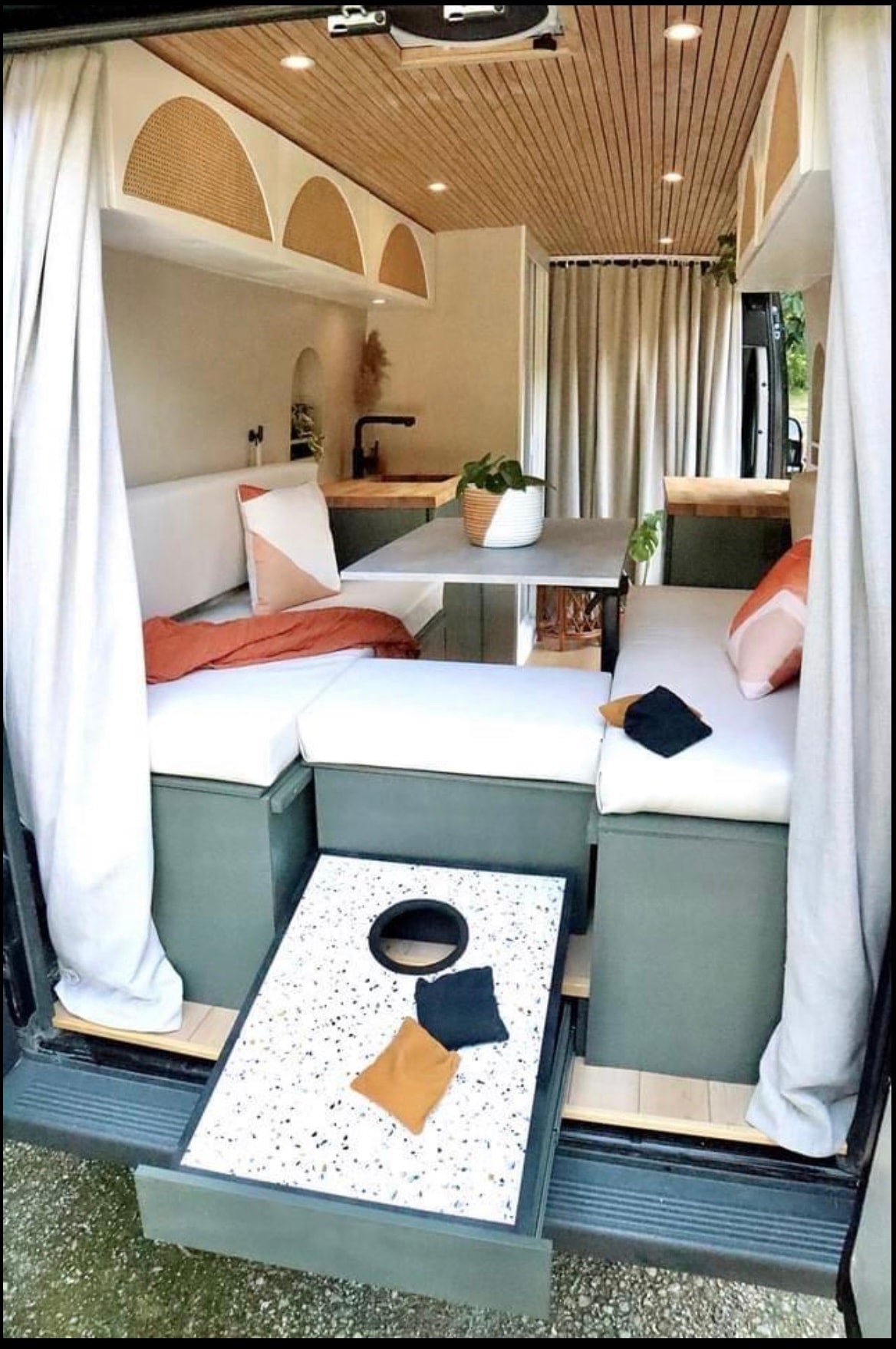 This RV rental camper van boasts a stylish interior with cozy seating, kitchen, and a pull-out cornhole game at the rear. — photo 3