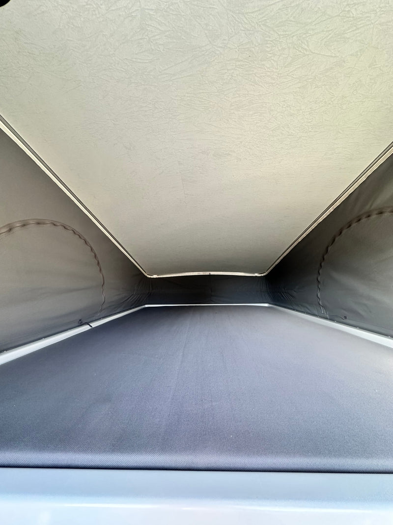 RV rental pop-top camper's interior: View of the light-colored elevated sleeping area and dark fabric walls. — photo 9