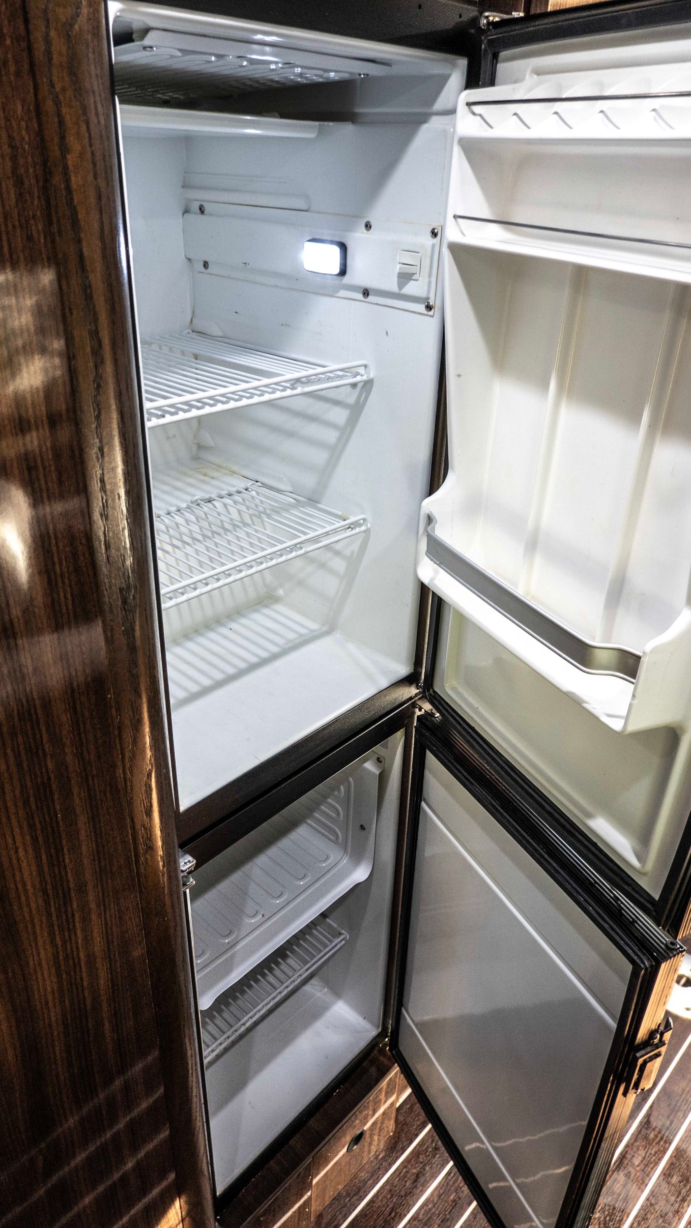 This rv rental offers a clean, empty refrigerator and freezer with wire shelving, perfect for storing food on your travels.