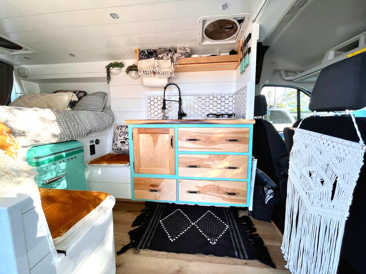 Stylish RV rental interior: bright kitchen, cozy bed, and clever storage solutions for your adventure.