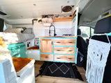 Stylish RV rental interior: bright kitchen, cozy bed, and clever storage solutions for your adventure.