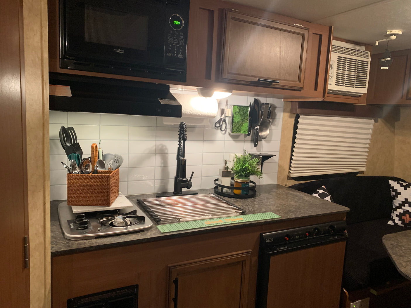 Detailed view of a well-equipped and organized kitchen inside an RV rental, featuring a microwave, stove, sink, and compact storage.
