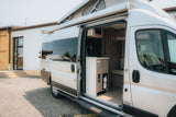 Explore this modern RV rental: open side door reveals a functional kitchenette, seating, and a pop-top roof.
