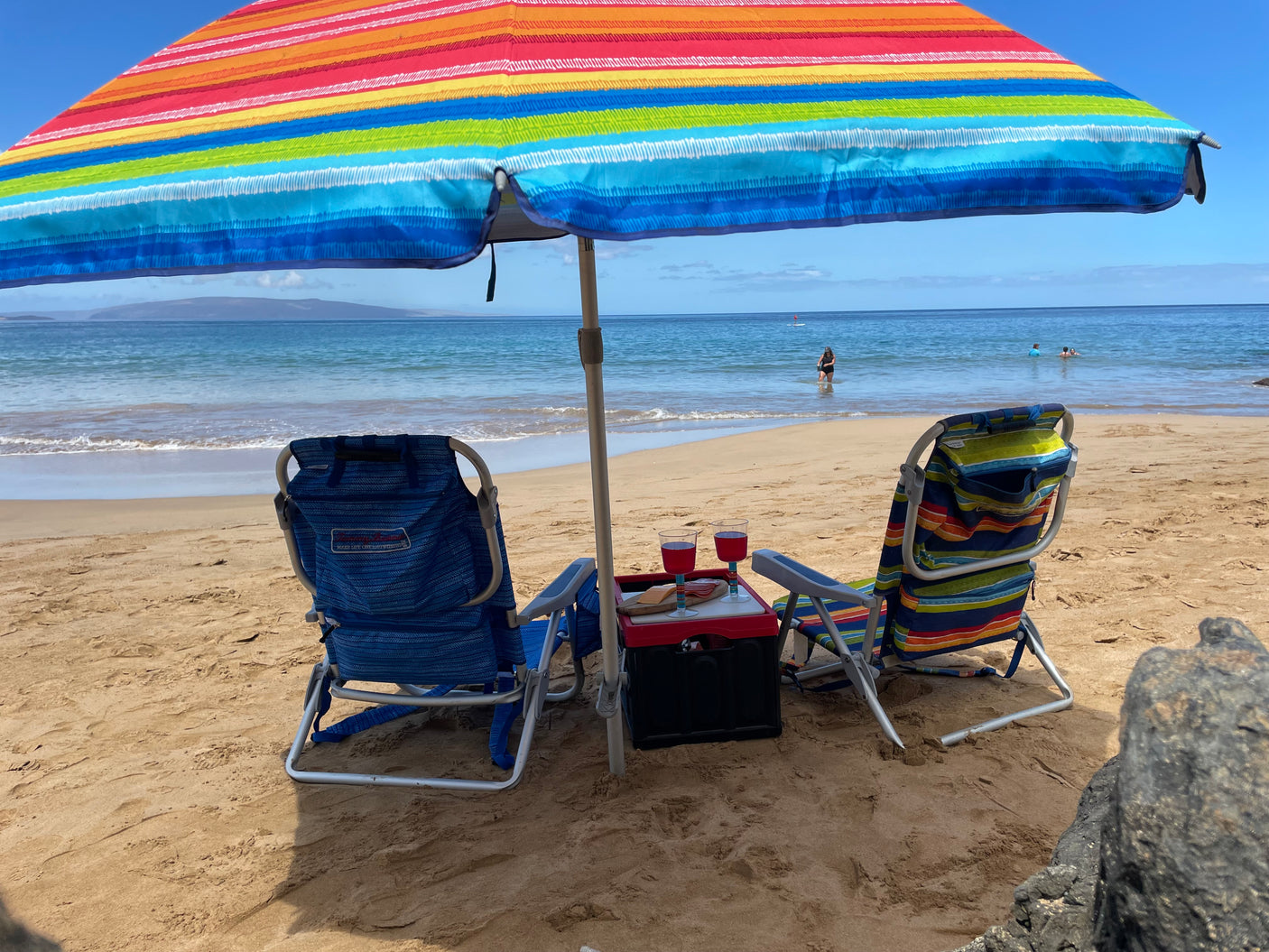 Serene beach scene with umbrella, chairs, and wine glasses. The perfect end to your RV rental vacation.