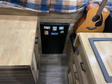 Explore this RV rental's cozy interior, featuring custom wood counters, a mini-fridge, and an acoustic guitar.