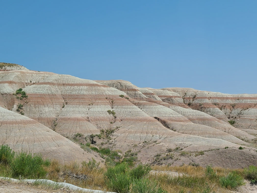 A beautiful landscape of stratified hills with red and white bands under a clear blue sky, ideal for an RV rental trip.