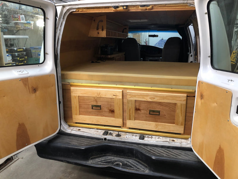 This RV rental camper van features a custom wood interior with a bed, drawers, and overhead storage, ready for adventure. — photo 8