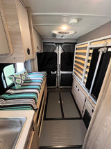 Cozy RV rental interior with a vibrant bed, practical sink, and smart storage, offering comfort for travel.