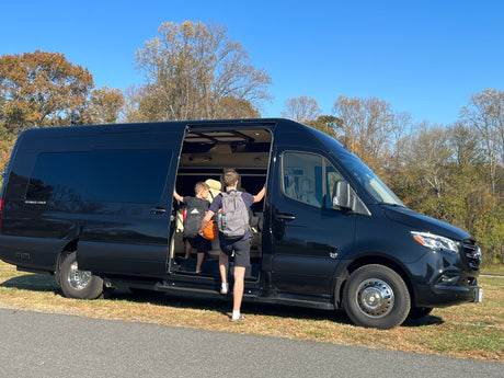 Luxury rv rental experience: Two boys board a spacious black Mercedes-Benz Sprinter van for their next adventure.
