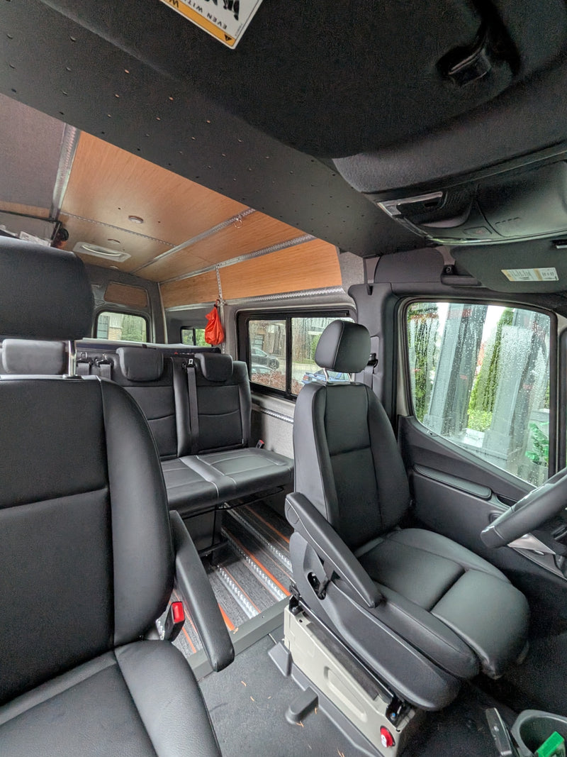 Inside an RV rental: versatile van interior with black leather seating, movable floor tracks, and cozy wood ceiling. — photo 6