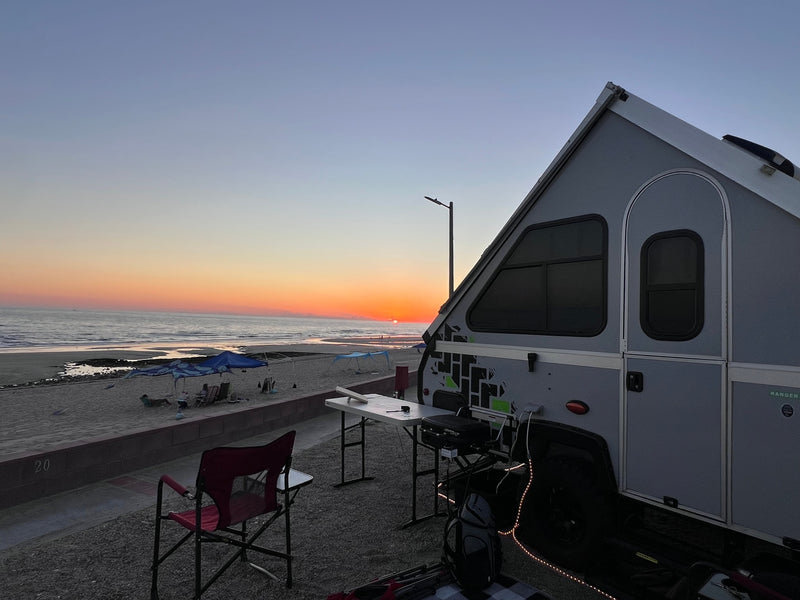  parked on a driveway.|A dark pickup truck tows a rugged A-Liner **RV rental** camping trailer — photo 6