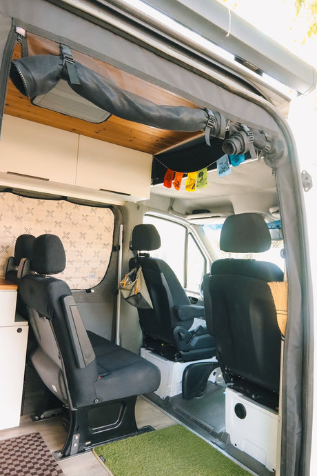  and functional control panel are next to a cozy bed.|Spacious RV rental camper van parked on a dirt road