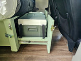 RV rental shows a custom bed base with a pull-out cooler and portable toilet, optimizing space in a van conversion.