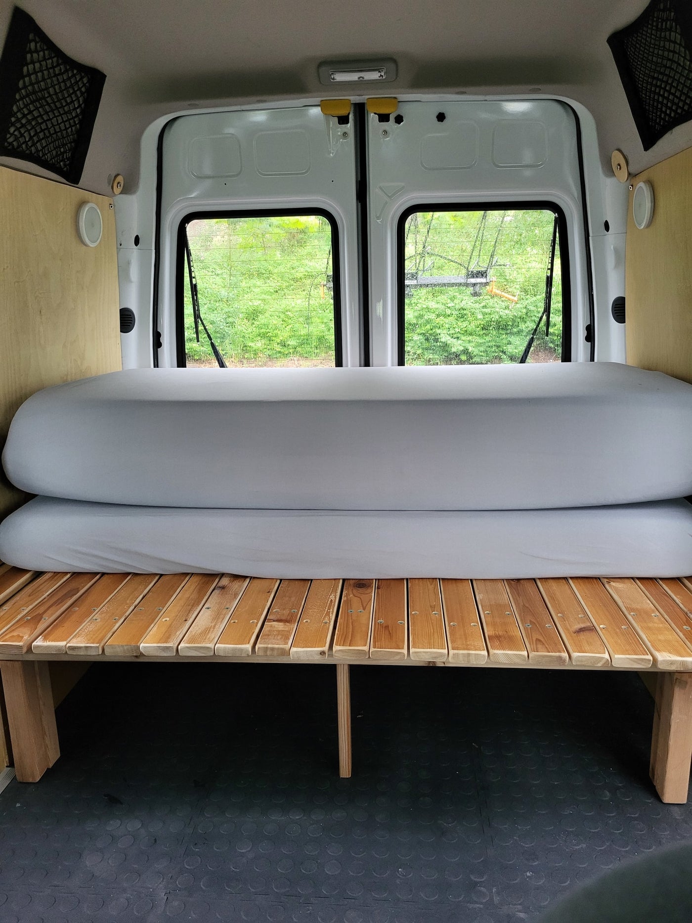  looking forward from the back over a grey sleeping platform to the front seats and dashboard.|Cozy camper van interior with a bed and pillows — photo 9