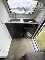Inside an RV rental: a modern, compact kitchen with a sink, Dometic cooktop, and Isotherm fridge.