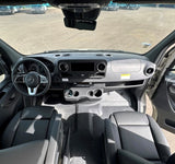 Inside an RV rental: view of the driver's cabin with modern dashboard, steering wheel, and front seating area.