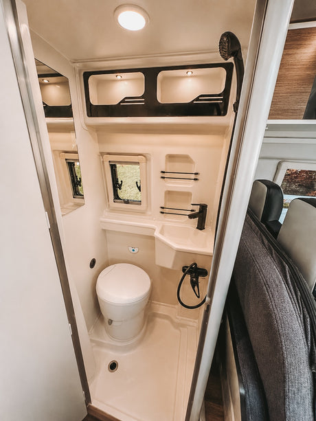 This rv rental features a compact, fully equipped RV bathroom with a toilet, sink, and shower for your journey.