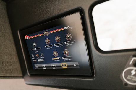 An RV rental's digital control panel displaying light settings for cargo, awning, and cabin areas. Modern touchscreen interface.